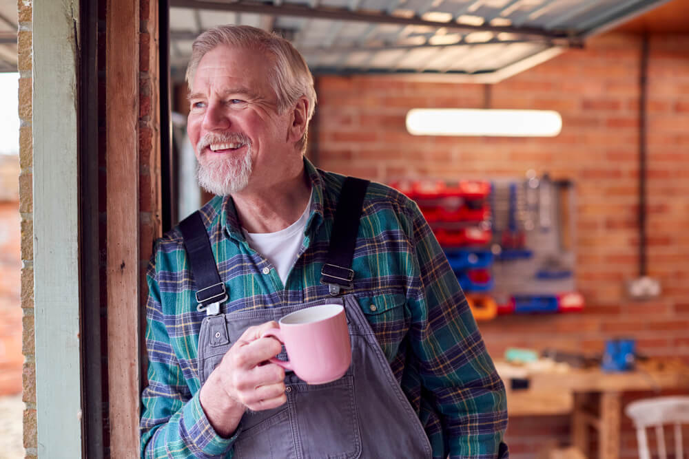Portrait Of Senior Male Wearing Overalls In Garage Workshop